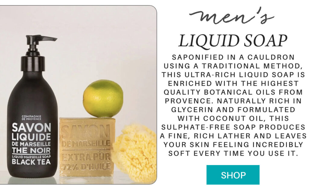 A black bottle of men’s liquid soap stands next to a beige bar of soap, a green apple, and a yellow sea sponge on a white surface. Text describes the soap’s natural ingredients and benefits. A blue "Shop" button is at the bottom. "Saponified in a cauldron using a traditional method, this ultra-rich liquid soap is enriched with the highest quality botanical oils from Provence. Naturally rich in glycerin and formulated with coconut oil, this sulphate-free soap produces a fine, rich lather and leaves your skin feeling incredibly soft every time you use it." Fearrington Village