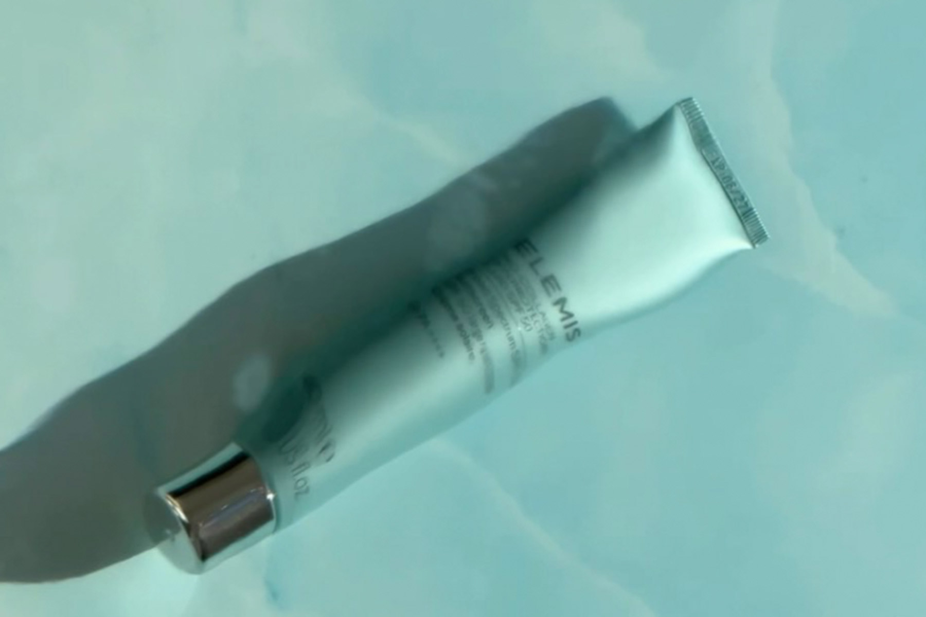 The Spa Edit - How to Transition Your Skincare Products as Seasons Change 1 A light blue tube of skincare cream with a silver cap lies diagonally on a light blue, marble-like surface, casting a soft shadow. Fearrington Village