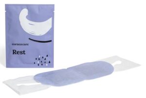 The Fearrington InnSider - The Ultimate Eye Mask You Didn’t Know You Needed 4 A purple packet labeled "Rest" stands behind an unfolded eye mask with a lavender hue, displayed on a white background. The package features a crescent shape and small, black raindrop-like designs. Fearrington Village