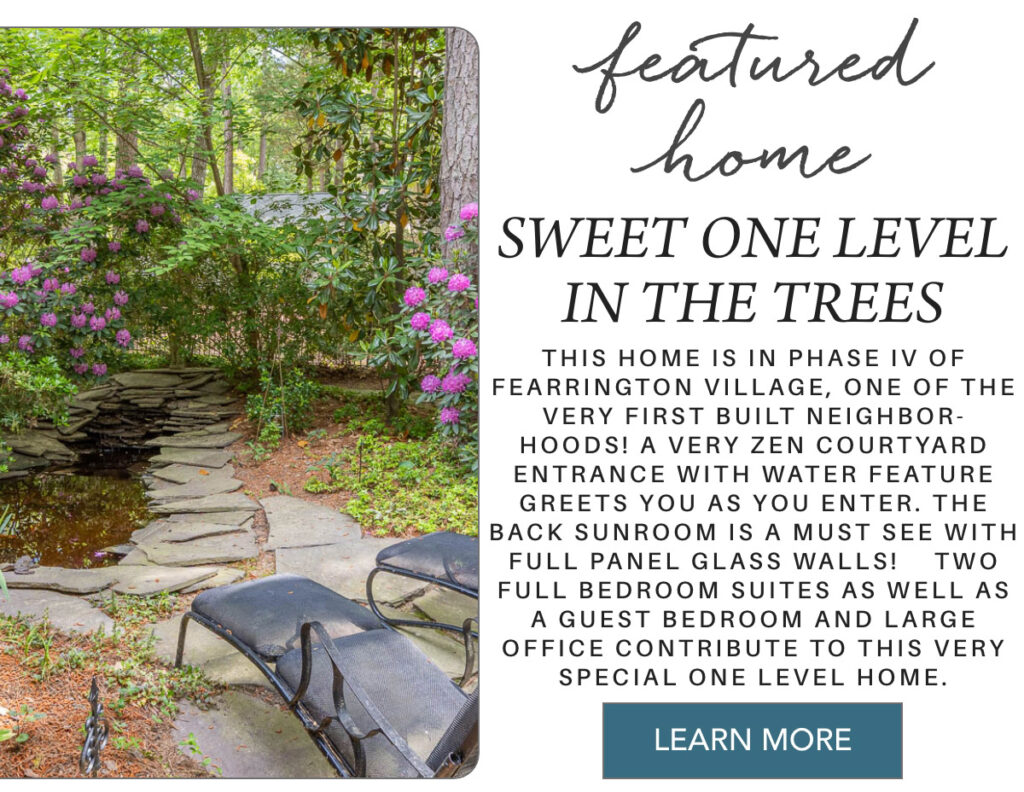 Two lounge chairs sit by a small stone pond with lush greenery and blooming purple flowers, promoting a featured single-level home in a wooded setting with water features and sunroom. Fearrington Village