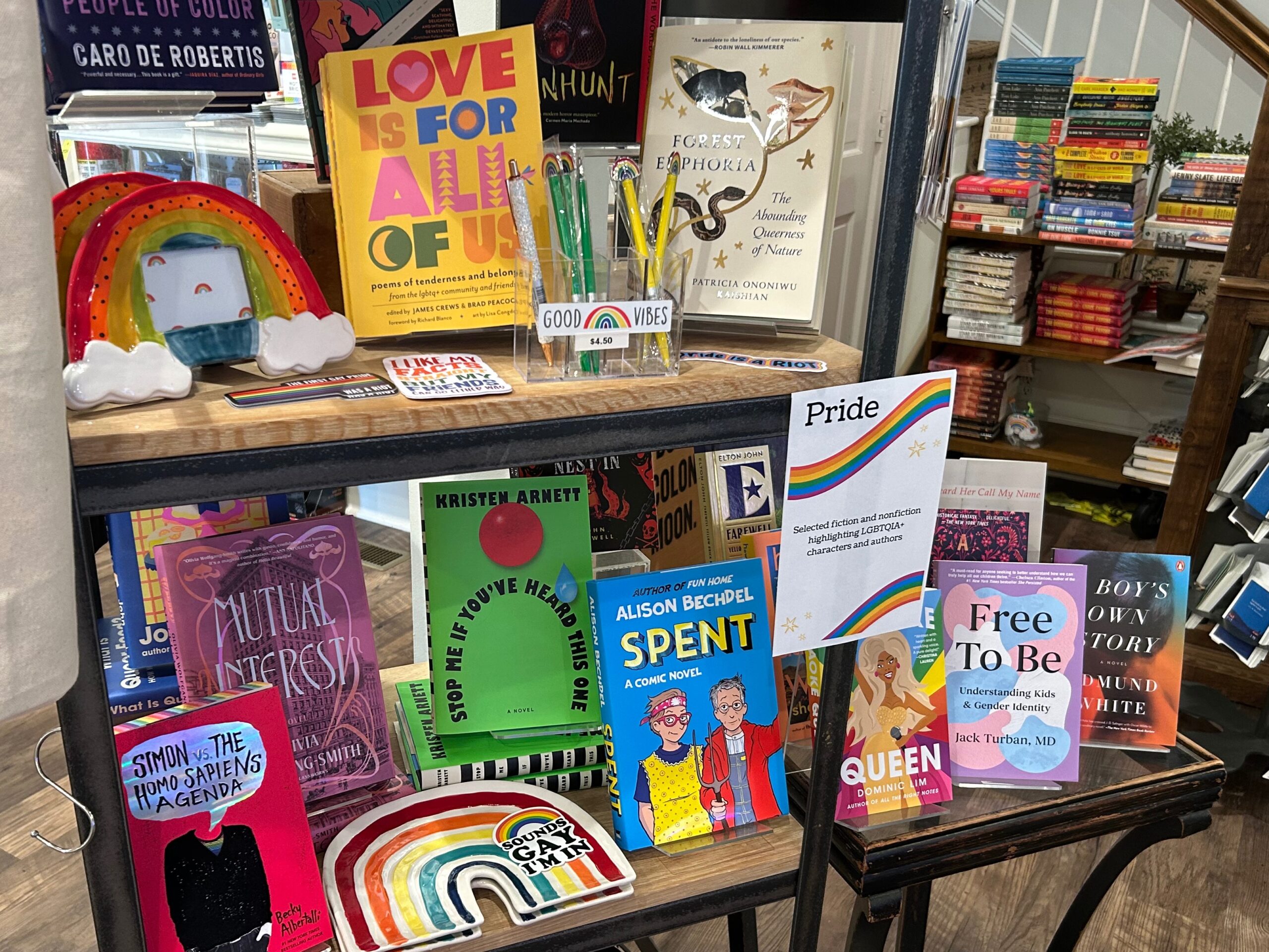 Gentle Reader - June 17, 2025 1 A bookstore display features LGBTQ+ books, a rainbow mug, and a “Good Vibes” pen holder. A “Pride” sign with a rainbow and information about LGBTQ+ community is also visible among colorful book covers and decorations. Fearrington Village