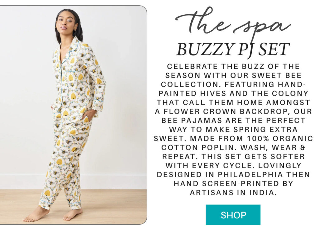 A woman stands barefoot wearing printed pajamas with a bee and floral pattern. Text beside her describes the "Buzzy PJ Set," made of organic cotton and designed with bee-themed art, available to shop. "Celebrate the buzz of the season with our Sweet Bee collection. Featuring hand-painted hives and the colony that call them home amongst a flower crown backdrop, our bee pajamas are the perfect way to make spring extra sweet. Made from 100% organic cotton poplin. Wash, wear & repeat. This set gets softer with every cycle. Lovingly designed in Philadelphia then hand screen-printed by artisans in India." Fearrington Village