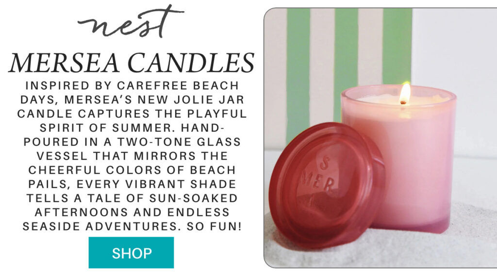 A pink MERSEA candle in a glass jar with a red lid sits on a white surface. Next to it is text describing the candle's beach-inspired fragrance and packaging, and a turquoise "SHOP" button. "Inspired by carefree beach days, mersea’s new Jolie Jar Candle captures the playful spirit of summer. Hand-poured in a two-tone glass vessel that mirrors the cheerful colors of beach pails, every vibrant shade tells a tale of sun-soaked afternoons and endless seaside adventures. so fun!" Fearrington Village