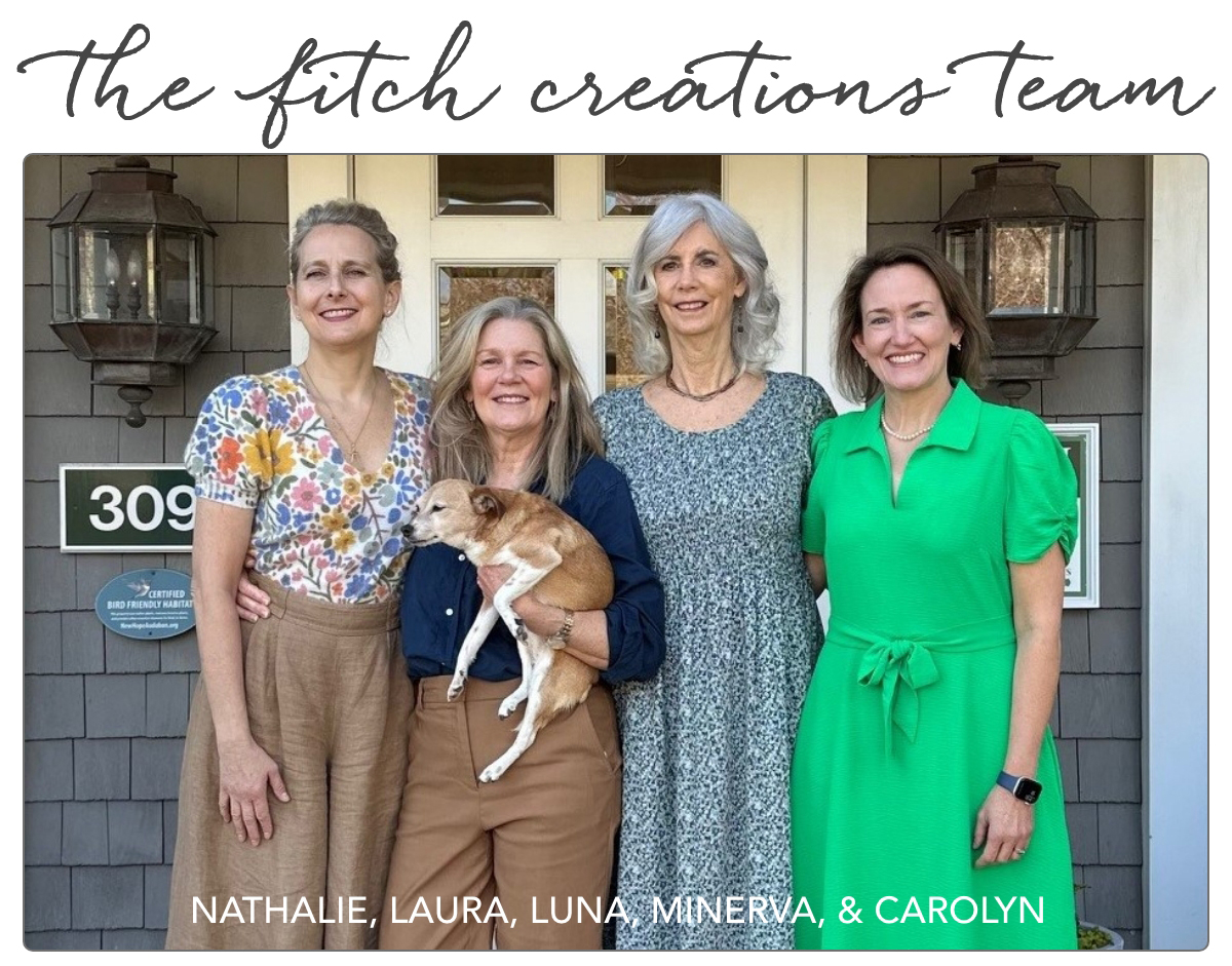 Four women stand together smiling in front of a gray house with a sign reading "309." One woman holds a small brown and white dog. Text above reads "The Fitch Creations Team;" names below: Nathalie, Laura, Luna, Minerva, & Carolyn. Fearrington Village