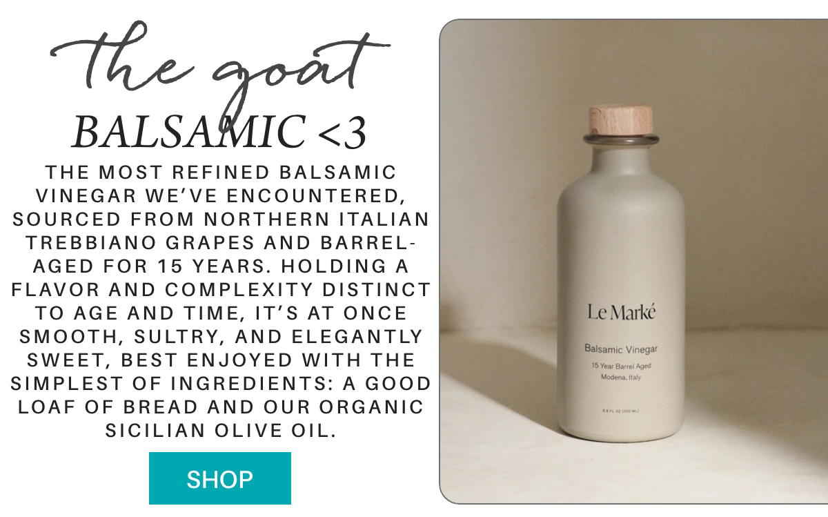 A bottle of Le Marké Balsamic Vinegar with a wooden cap sits on a light surface. Text describes it as 15-year barrel-aged, made from Italian grapes, ideal with bread and organic olive oil. A turquoise "SHOP" button is below. "The most refined Balsamic Vinegar we’ve encountered, sourced from Northern Italian Trebbiano grapes and barrel-aged for 15 years. Holding a flavor and complexity distinct to age and time, it’s at once smooth, sultry, and elegantly sweet, best enjoyed with the simplest of ingredients: a good loaf of bread and our organic Sicilian Olive Oil." Fearrington Village