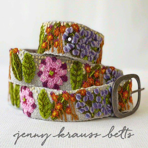 A belt with a silver buckle, decorated with colorful embroidered flowers and leaves, displayed on a white surface. Text at the bottom reads "jenny krauss belts. Fearrington Village