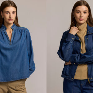 Two women stand against a plain background. The woman on the left wears a blue denim blouse and tan pants, while the woman on the right wears a blue denim jacket over a tan turtleneck and blue jeans. Fearrington Village