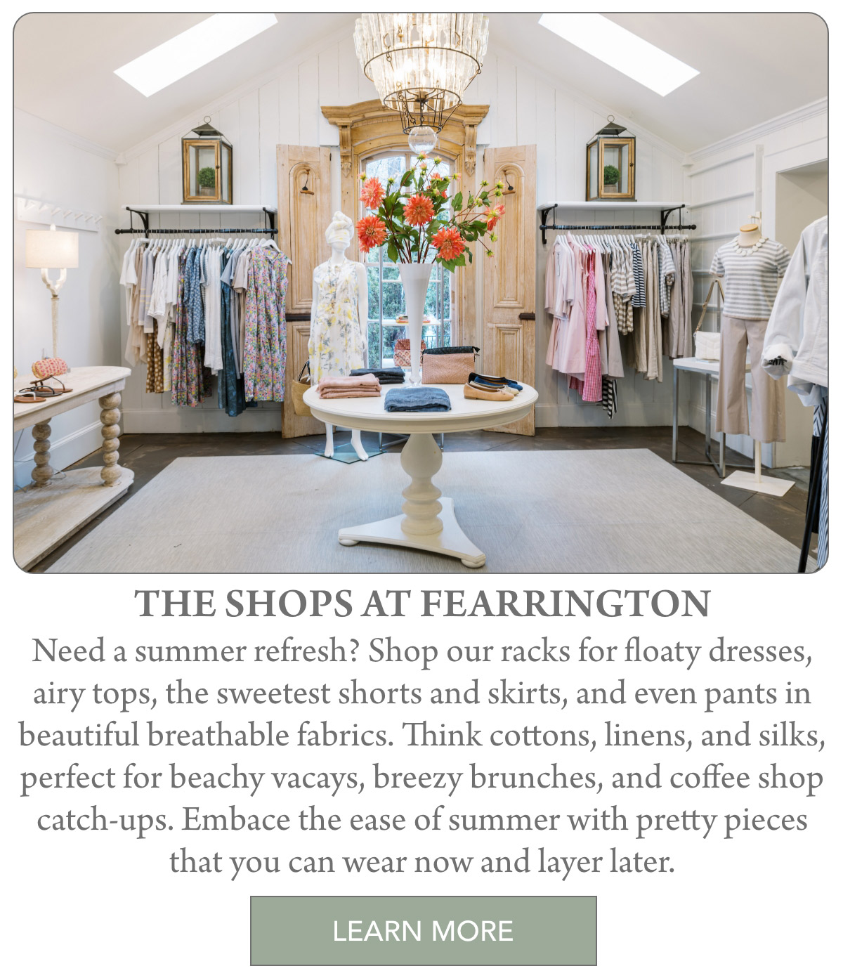 A bright boutique with light wood accents displays summer dresses, tops, and pants on racks. A central table holds a vase of orange flowers and folded clothes, creating a fresh, inviting shopping atmosphere. Fearrington Village