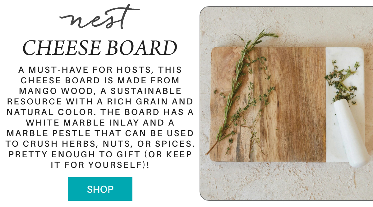 A rectangular cheese board with a white marble inlay and marble pestle, topped with herbs, sits on a white surface next to descriptive text about the board’s features. "a must-have for hosts, this cheese board is made from mango wood, a sustainable resource with a rich grain and natural color. The board has a white marble inlay and a marble pestle that can be used to crush herbs, nuts, or spices. pretty enough to gift (or keep it for yourself)!" Fearrington Village