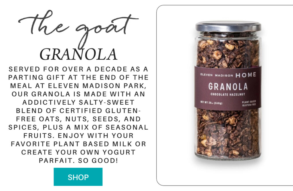 A glass jar of Eleven Madison Home Chocolate Hazelnut Granola is shown next to text describing it as a gluten-free, plant-based granola made with oats, nuts, seeds, spices, and seasonal fruits. A blue “Shop” button is below. "Served for over a decade as a parting gift at the end of the meal at Eleven Madison Park, our granola is made with an addictively salty-sweet blend of certified gluten-free oats, nuts, seeds, and spices, plus a mix of seasonal fruits. Enjoy with your favorite plant based milk or create your own yogurt parfait. so good!" Fearrington Village
