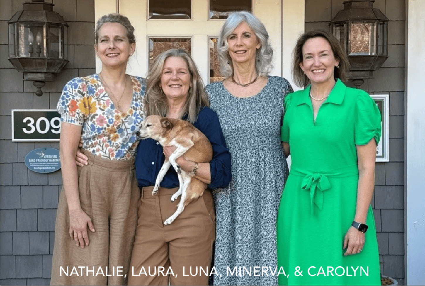 Four smiling women stand together in front of a house; one holds a small tan dog. They wear summer outfits in patterns and solids, and the house number “309” is visible behind them. Text reads: "Nathalie, Laura, Luna, Minerva, & Carolyn. Fearrington Village