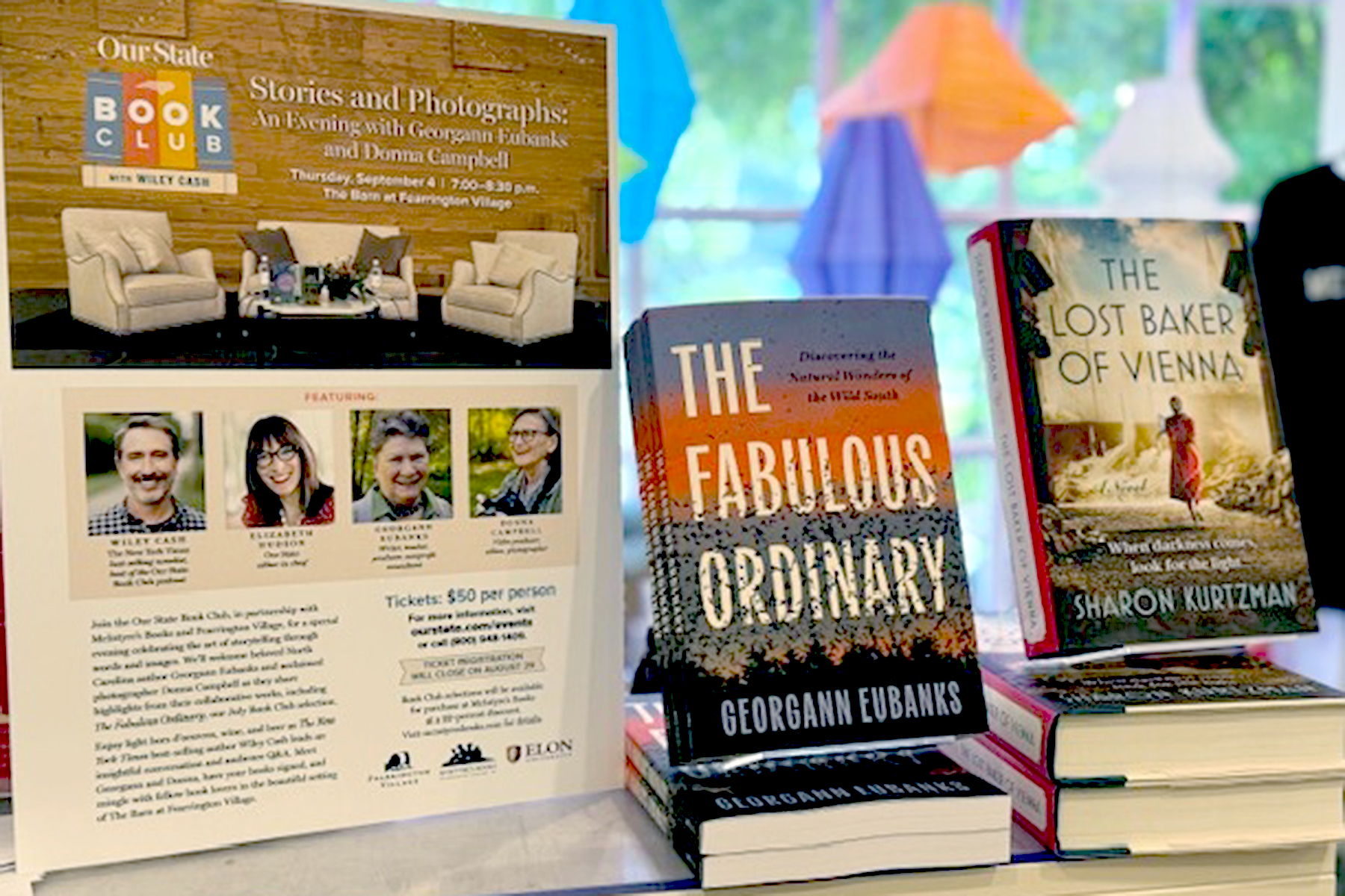 A table display features two books, "The Fabulous Ordinary" and "The Lost Baker of Vienna," along with an event flyer promoting a book club evening with authors Georgann Eubanks and Donna Campbell. Fearrington Village