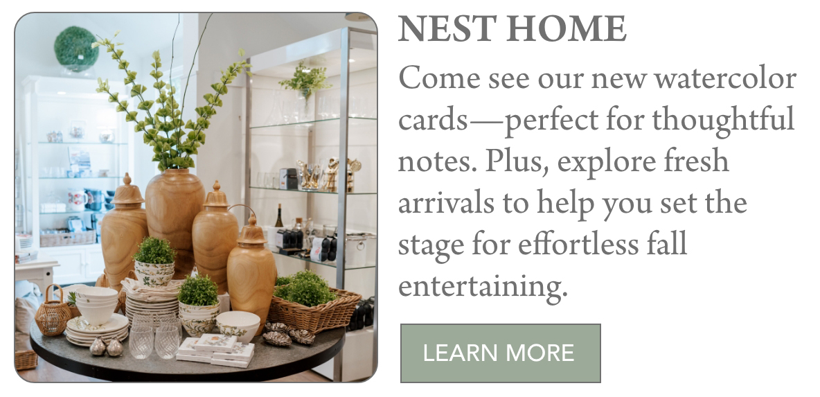 A display of decorative jars, dishes, and greenery on a round table in a home store, with shelves of items in the background. Text invites shoppers to explore new watercolor cards and fall arrivals at Nest Home. "Come see our new watercolor cards—perfect for thoughtful notes. Plus, explore fresh arrivals to help you set the stage for effortless fall entertaining." Fearrington Village
