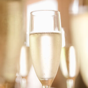 Wine Class - Bubbles! - December 18, 2025 6 A close-up of a clear champagne flute filled with sparkling wine, surrounded by several other blurred glasses. The light background creates a celebratory and elegant atmosphere. Fearrington Village