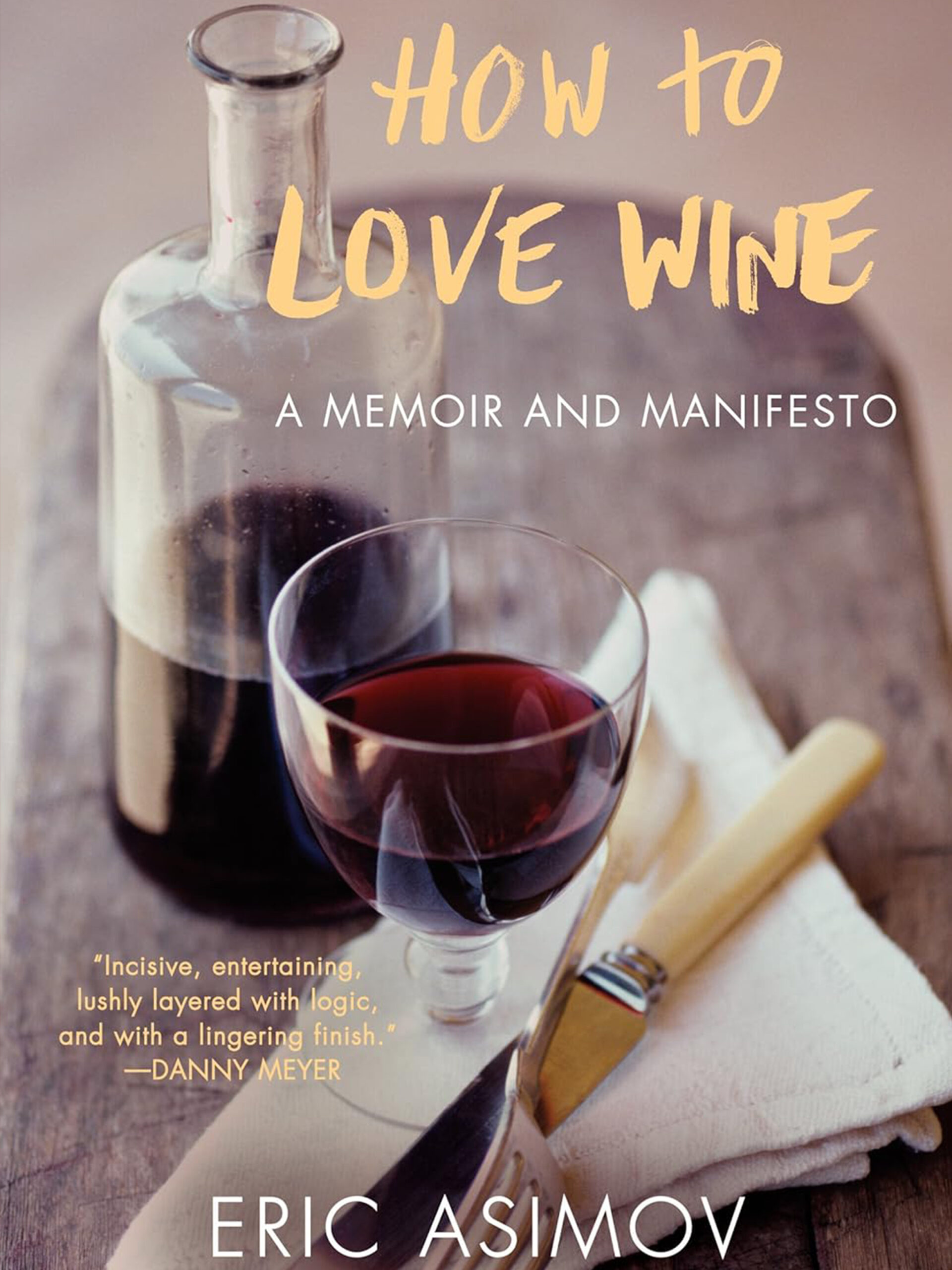 A book cover for "How to Love Wine: A Memoir and Manifesto" by Eric Asimov features a glass and a carafe of red wine on a wooden table with a folded napkin and a knife beside them. Fearrington Village