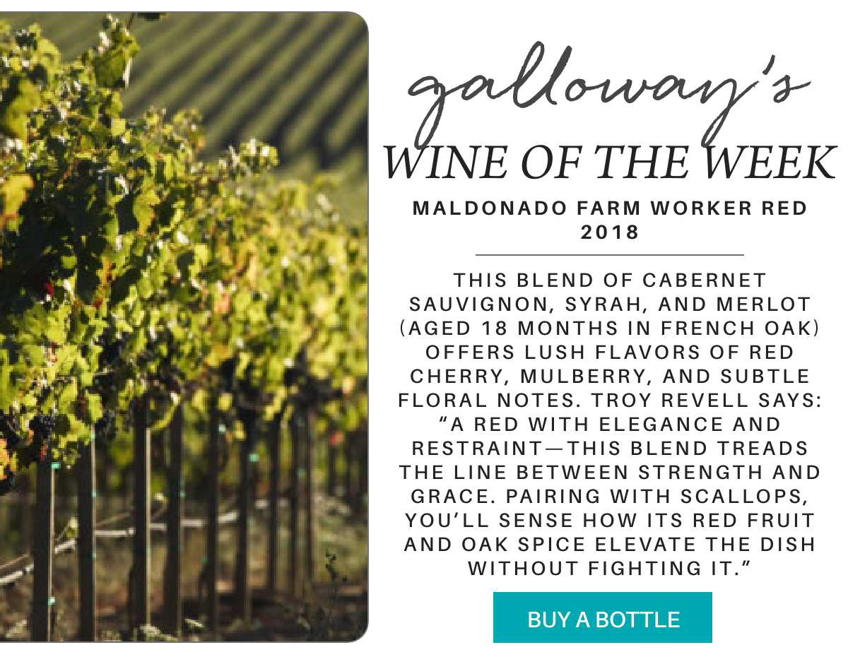 Rows of grapevines in a vineyard on the left; on the right, text describing “Galloway’s Wine of the Week,” highlighting the 2018 Maldonado Farm Worker Red and its tasting notes, with a “Buy a Bottle” button below. "This blend of Cabernet Sauvignon, Syrah, and Merlot (aged 18 months in French oak) offers lush flavors of red cherry, mulberry, and subtle floral notes. Troy revell says: “A red with elegance and restraint—this blend treads the line between strength and grace. Pairing with scallops, you’ll sense how its red fruit and oak spice elevate the dish without fighting it.”" Fearrington Village