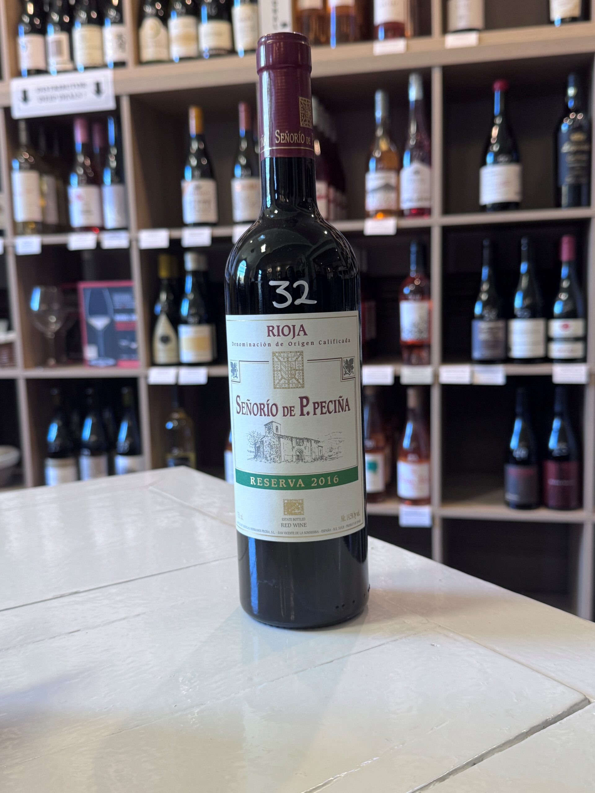 The Fearrington Plate - October 23, 2025 2 A bottle of Señorio de P. Peciña Rioja Reserva 2016 red wine stands on a white table, with shelves of assorted wine bottles visible in the background. Fearrington Village