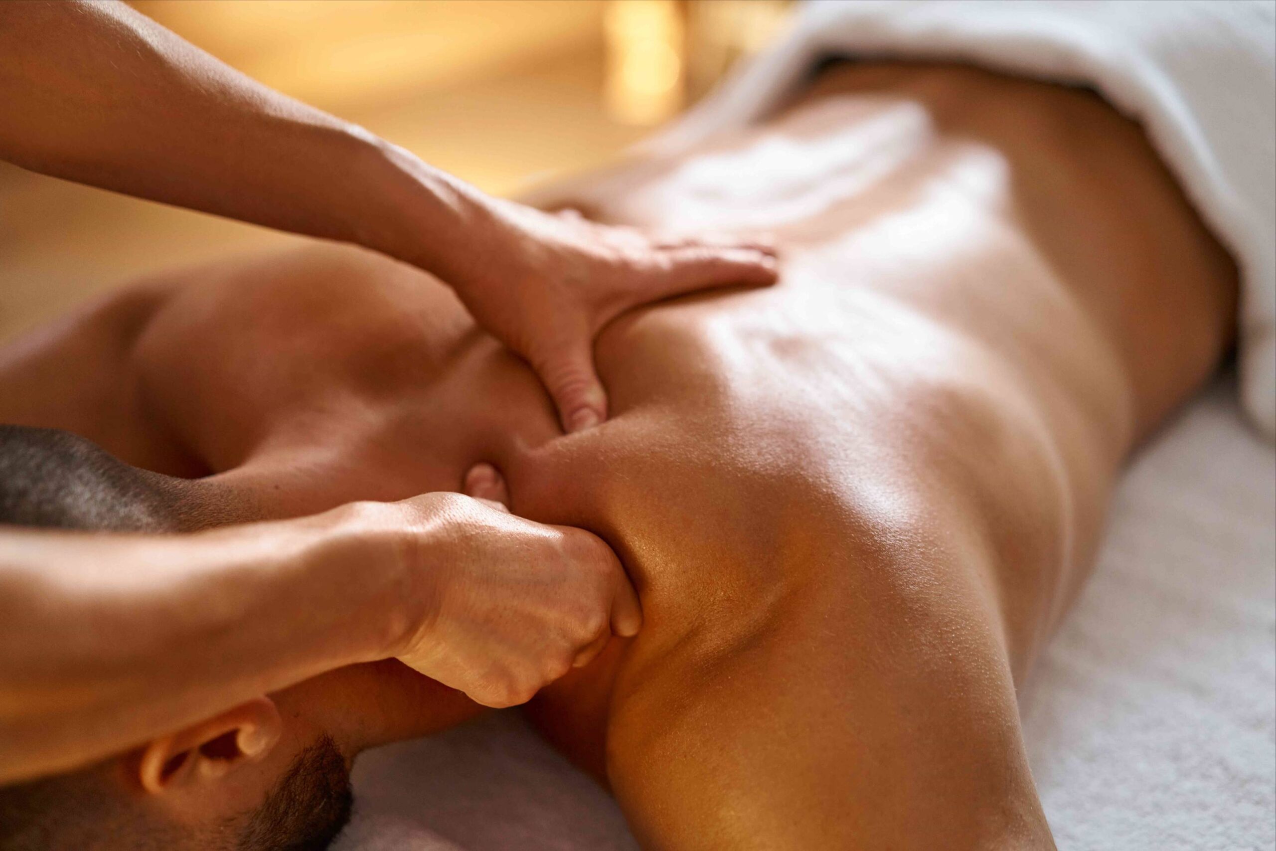 The Spa Edit - Swedish vs. Deep Tissue Massage: Which Is Right for You? 2 A person receives a deep tissue massage on their bare upper back while lying face down on a massage table. The masseuse’s hands are applying firm pressure near the shoulder blades. Fearrington Village