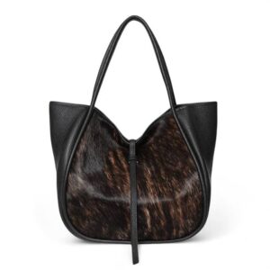 A stylish black leather tote bag with brown and black fur textured front panel, featuring two long handles and a simple, elegant design. Fearrington Village